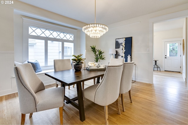 dining area with light hardwood / wood-style flooring and an inviting chandelier