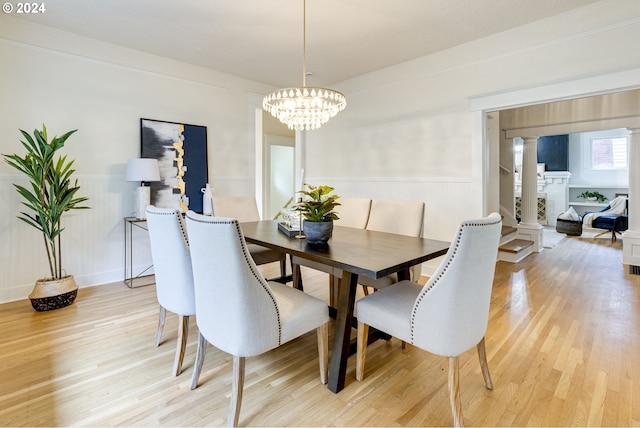 dining area featuring light hardwood / wood-style floors, a notable chandelier, and decorative columns