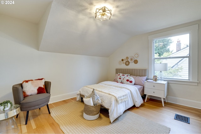 bedroom with vaulted ceiling and hardwood / wood-style flooring