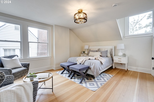 bedroom featuring an inviting chandelier, lofted ceiling, and hardwood / wood-style flooring