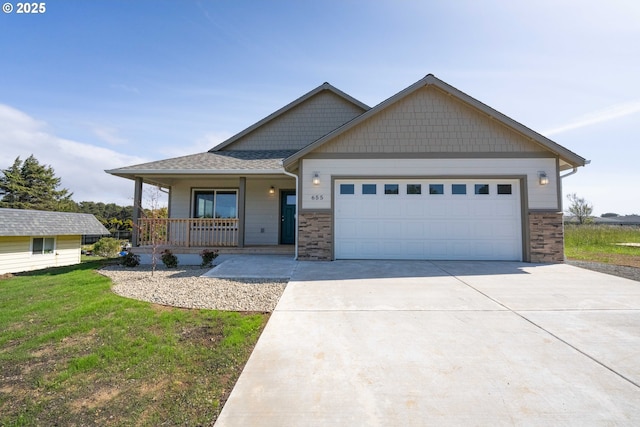 655 11th St SW, Bandon, OR 97411 - craftsman-style home with covered porch, driveway, an attached garage, and stone siding