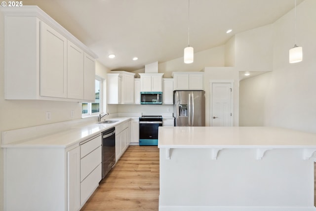 655 11th St SW, Bandon, OR 97411 - kitchen featuring appliances with stainless steel finishes, a breakfast bar area, light wood finished floors, white cabinetry, and lofted ceiling