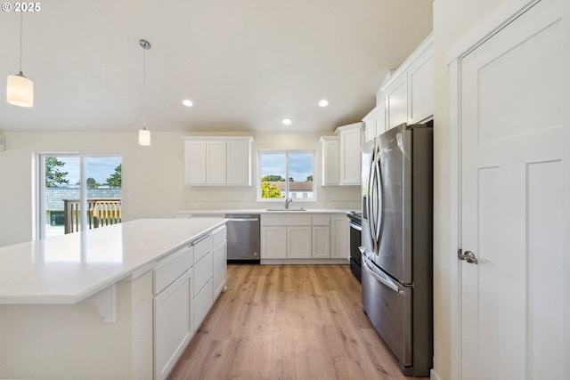 655 11th St SW, Bandon, OR 97411 - kitchen with stainless steel appliances, a sink, a kitchen island, light wood-type flooring, and white cabinets