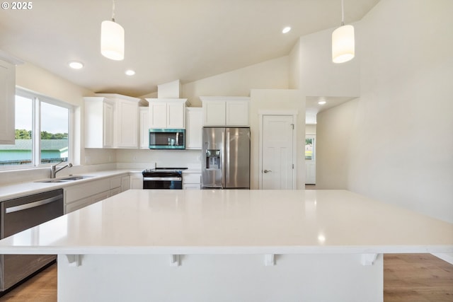 655 11th St SW, Bandon, OR 97411 - kitchen featuring appliances with stainless steel finishes, a sink, a kitchen island, white cabinetry, and a breakfast bar area
