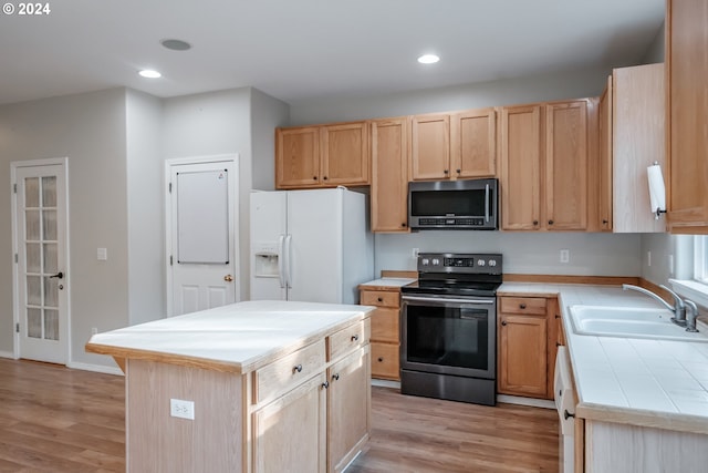 kitchen featuring light hardwood / wood-style flooring, appliances with stainless steel finishes, a kitchen island, and sink