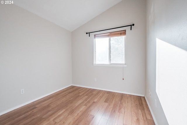 spare room featuring vaulted ceiling and light hardwood / wood-style flooring