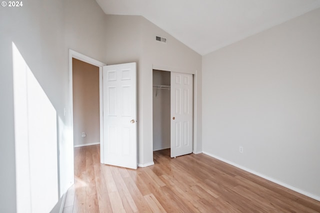 unfurnished bedroom with a closet, light wood-type flooring, and high vaulted ceiling