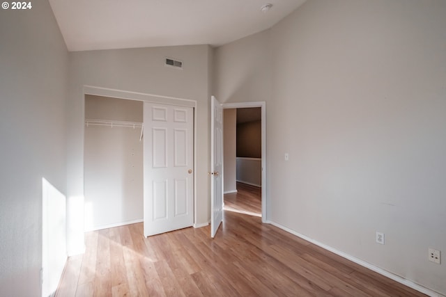 unfurnished bedroom with light hardwood / wood-style floors, a closet, and high vaulted ceiling