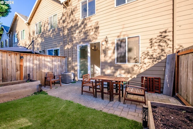 rear view of house featuring cooling unit, a lawn, and a patio