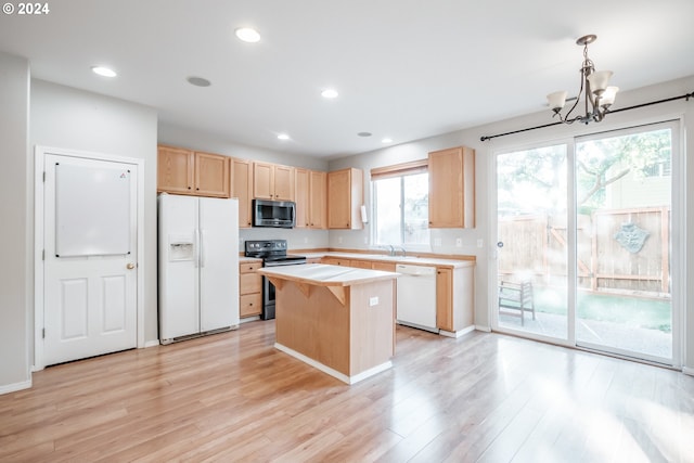 kitchen with decorative light fixtures, a chandelier, appliances with stainless steel finishes, a center island, and light hardwood / wood-style floors