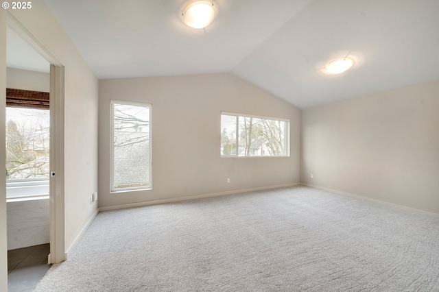 spare room featuring lofted ceiling and light carpet