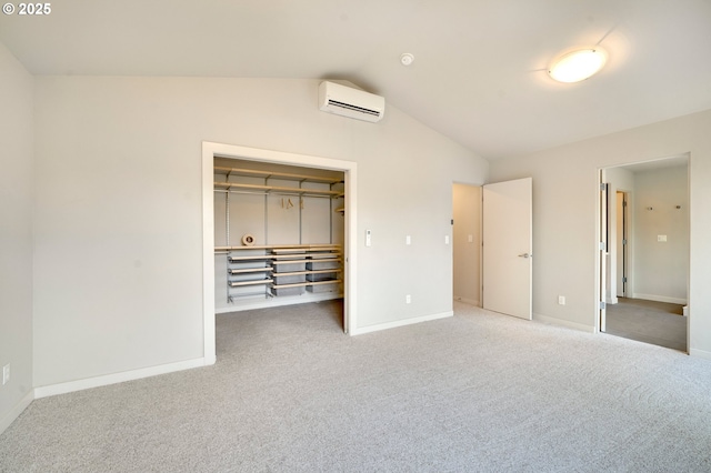 unfurnished bedroom with carpet flooring, vaulted ceiling, a spacious closet, an AC wall unit, and a closet