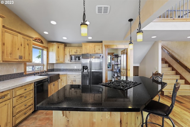 kitchen featuring a center island, light brown cabinetry, light hardwood / wood-style floors, and black appliances