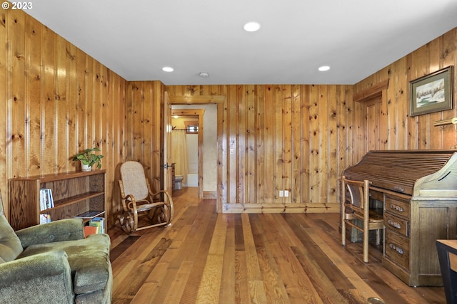 living room with dark hardwood / wood-style flooring and wood walls