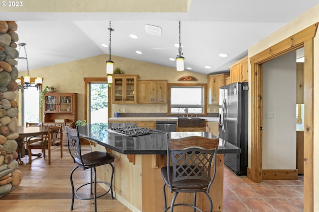 kitchen featuring lofted ceiling, hanging light fixtures, a kitchen breakfast bar, light wood-type flooring, and stainless steel appliances