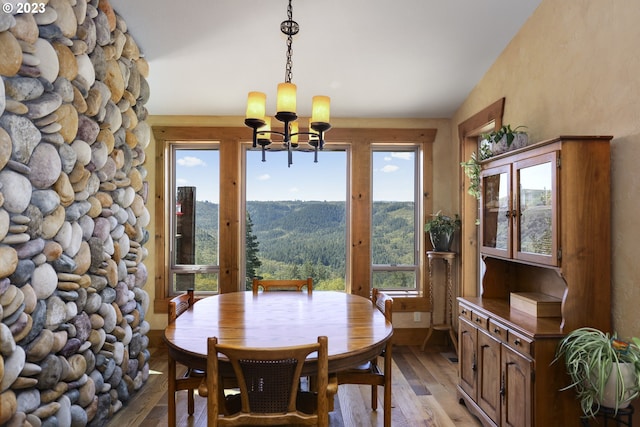 dining area featuring a mountain view, light wood-type flooring, a chandelier, and lofted ceiling