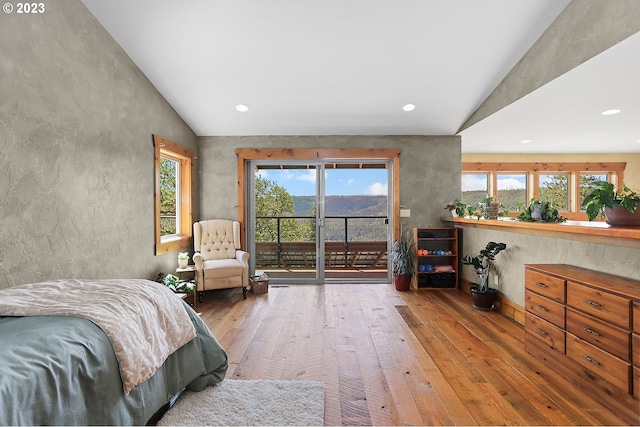 bedroom with hardwood / wood-style floors, access to exterior, and lofted ceiling