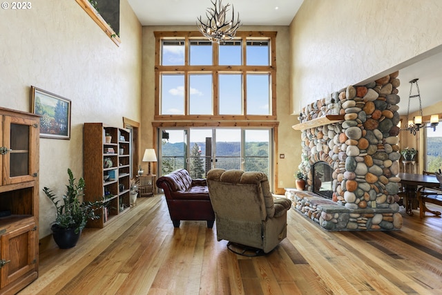 living room with a high ceiling, a chandelier, and light hardwood / wood-style flooring