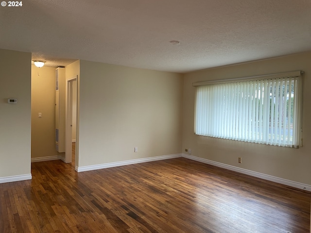 spare room with a textured ceiling and dark wood-type flooring