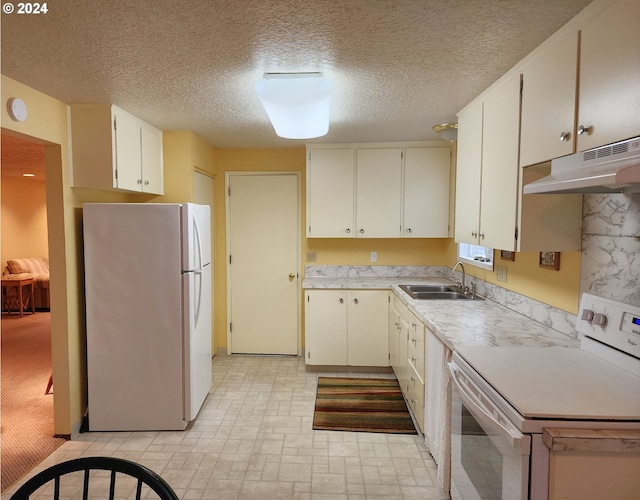 kitchen featuring white appliances, light colored carpet, sink, a textured ceiling, and white cabinetry