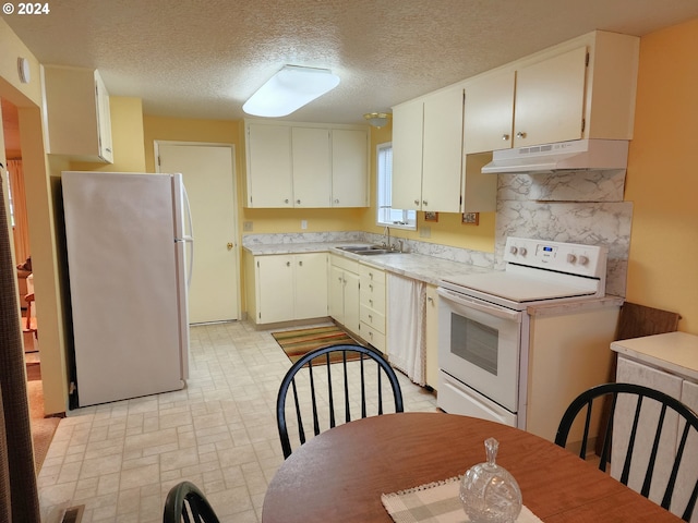 kitchen with white appliances, sink, light tile floors, a textured ceiling, and white cabinetry