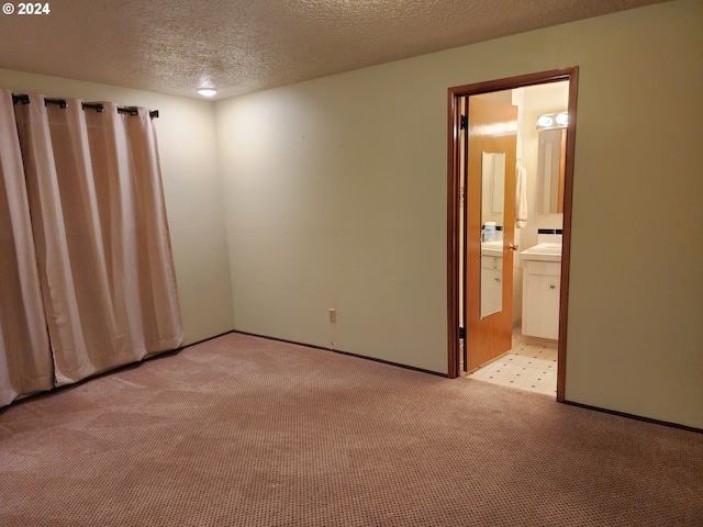 spare room with light colored carpet and a textured ceiling