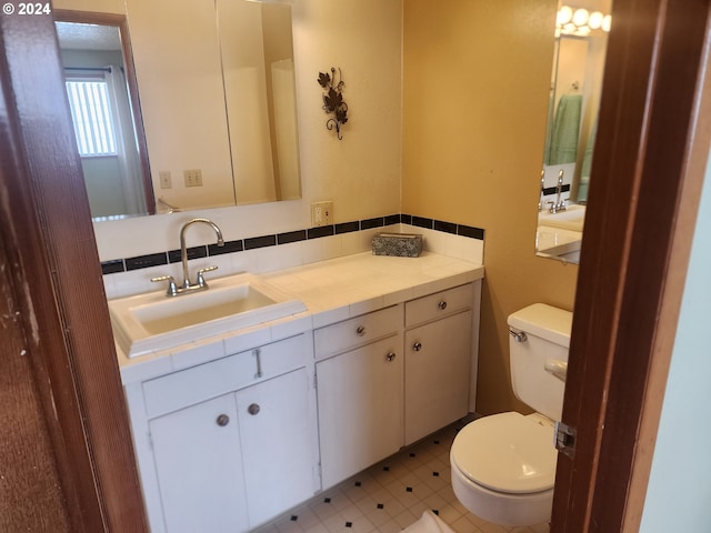 bathroom with toilet, tasteful backsplash, vanity with extensive cabinet space, and tile flooring