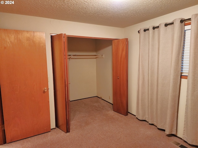 unfurnished bedroom with a closet, light carpet, and a textured ceiling