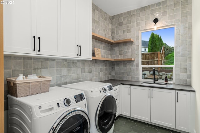 laundry room featuring cabinets, dark tile patterned flooring, sink, and independent washer and dryer