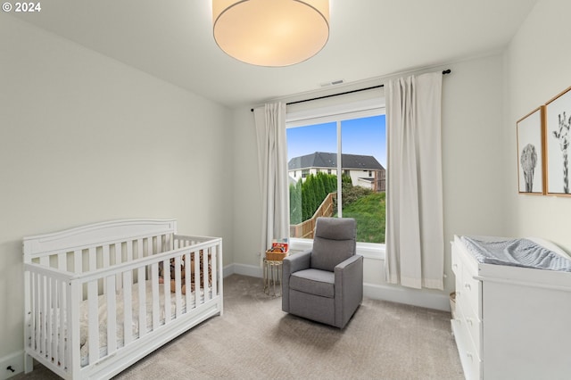 bedroom with light carpet and a nursery area