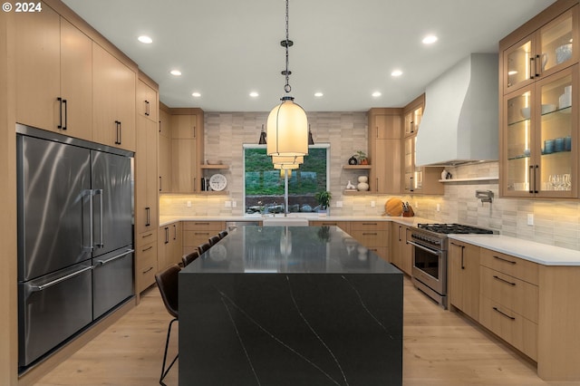 kitchen featuring premium appliances, custom exhaust hood, light wood-type flooring, and a kitchen island