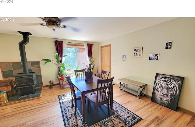 dining room with a wood stove, light hardwood / wood-style flooring, and ceiling fan