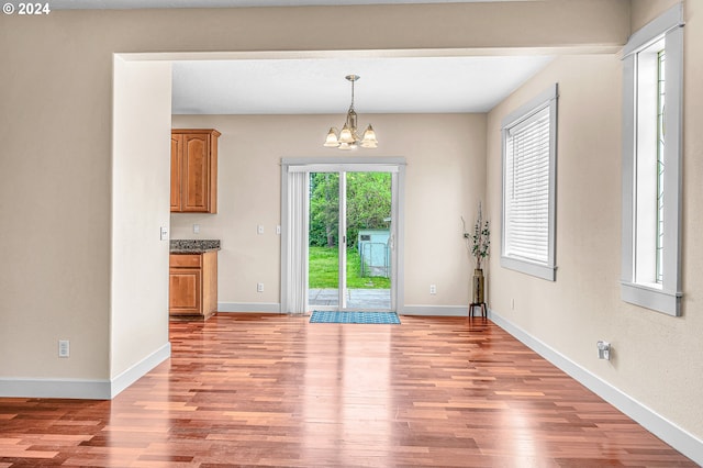 unfurnished dining area with a chandelier and light wood-type flooring