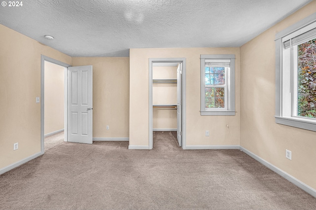 unfurnished bedroom featuring a closet, light colored carpet, and a walk in closet