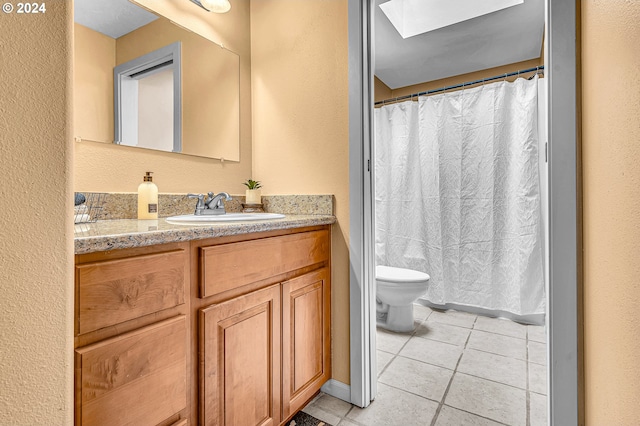 bathroom with a skylight, tile patterned floors, vanity, and toilet