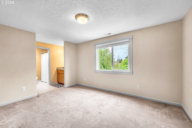 unfurnished room with a textured ceiling and light colored carpet