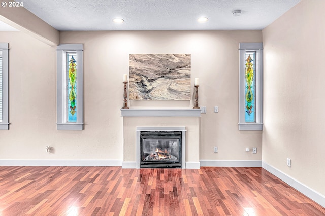 unfurnished living room with hardwood / wood-style floors and a textured ceiling