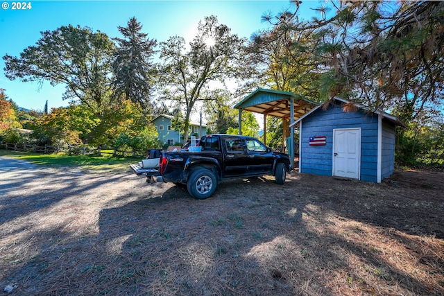 view of yard featuring a storage shed, an outdoor structure, fence, and a detached carport