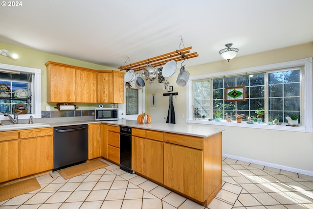 kitchen featuring black dishwasher, stainless steel microwave, a peninsula, a sink, and light countertops
