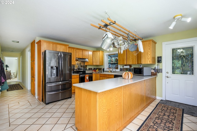 kitchen with stainless steel appliances, a peninsula, under cabinet range hood, light tile patterned flooring, and light countertops