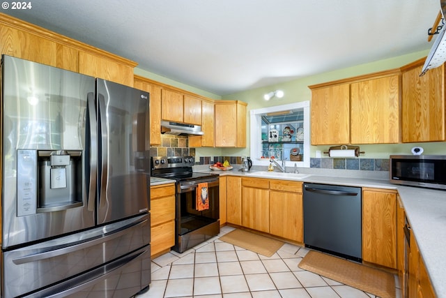 kitchen with appliances with stainless steel finishes, under cabinet range hood, a sink, light countertops, and light tile patterned floors