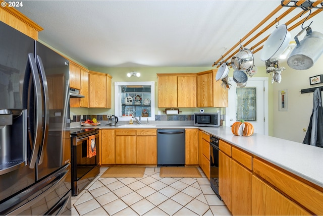 kitchen with appliances with stainless steel finishes, a sink, light countertops, and under cabinet range hood