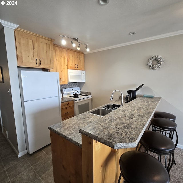 kitchen with a kitchen breakfast bar, ornamental molding, a sink, white appliances, and baseboards