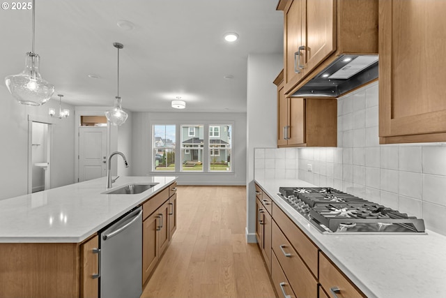 kitchen with appliances with stainless steel finishes, pendant lighting, sink, custom exhaust hood, and a kitchen island with sink