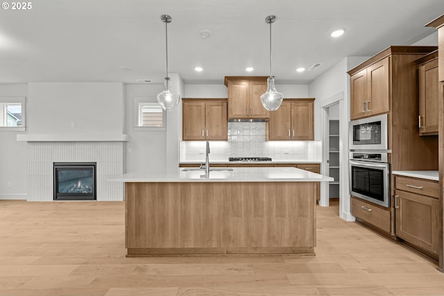 kitchen featuring pendant lighting, stainless steel appliances, and a center island with sink