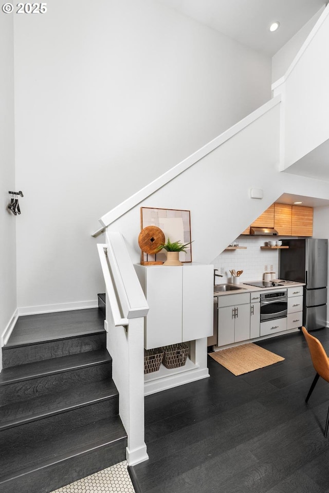 stairway featuring a towering ceiling, hardwood / wood-style flooring, and sink