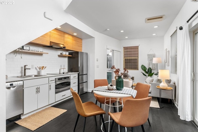 kitchen featuring appliances with stainless steel finishes, dark hardwood / wood-style flooring, decorative backsplash, sink, and white cabinetry