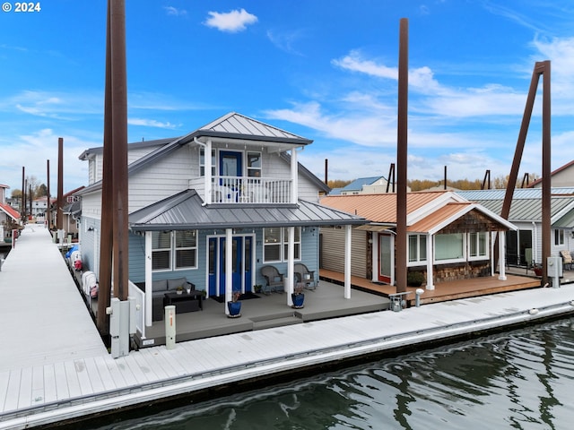 back of property featuring outdoor lounge area, a balcony, and a water view