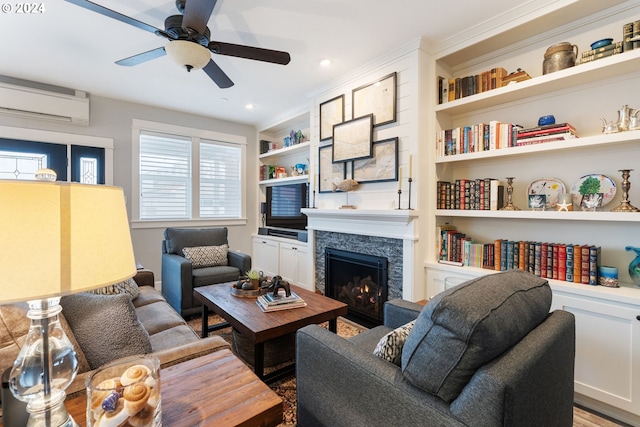 living room featuring crown molding, built in shelves, ceiling fan, wood-type flooring, and a wall unit AC