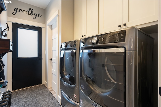 clothes washing area with washing machine and clothes dryer, carpet flooring, and cabinets